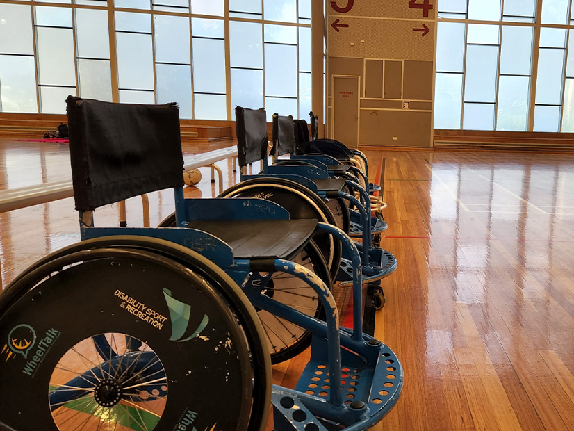 Wheeltalk wheelchairs lined up in a row on a stadium court